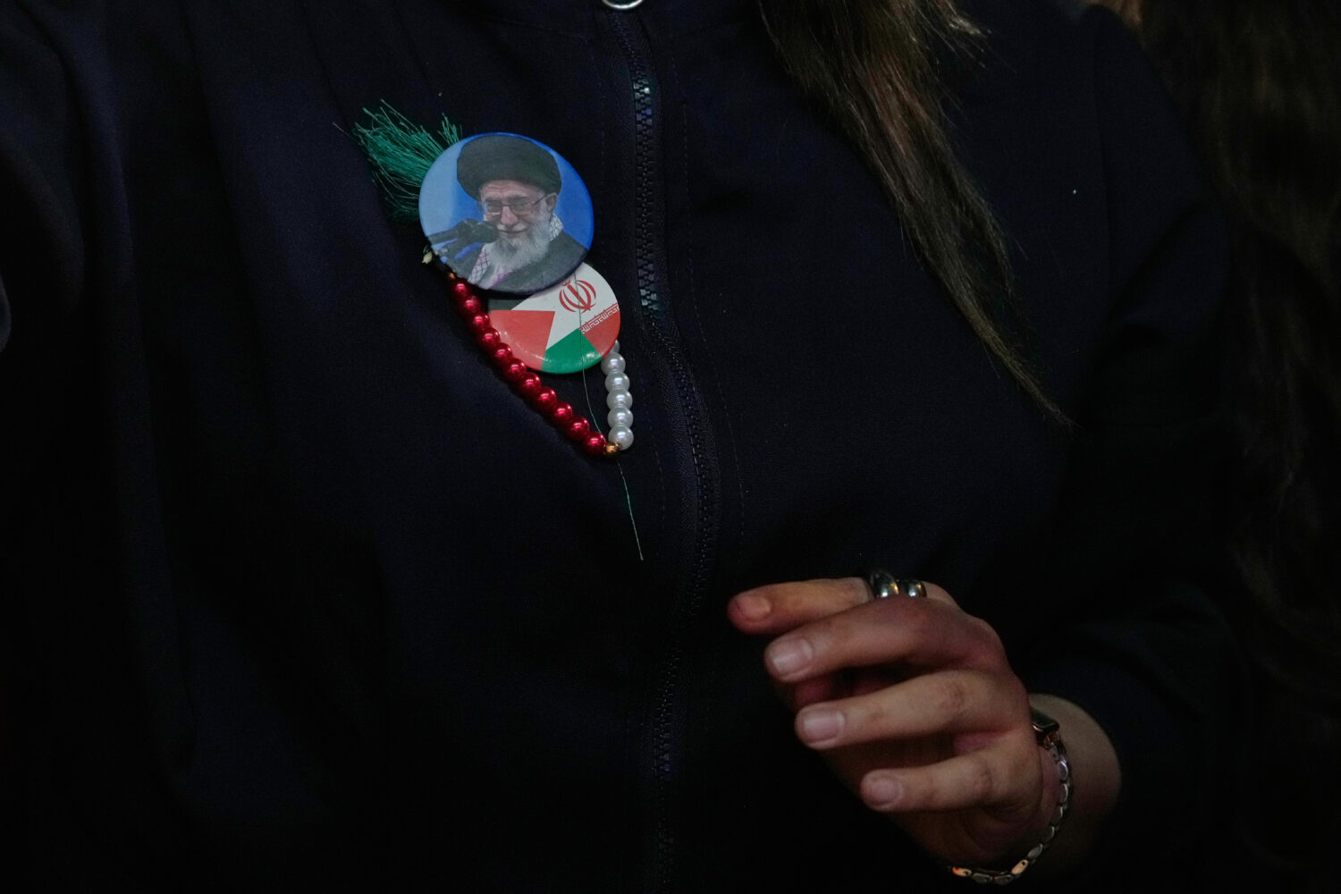 A government supporter wears badges showing a portrait of the slain Iranian Supreme Leader Ayatolla...