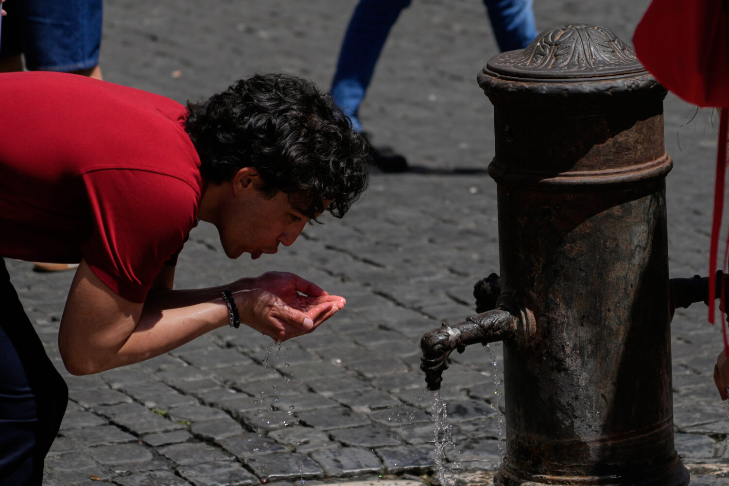 A man drinks water at a fountain in downtown Rome as temperatures are expected to reach 32 degrees ...