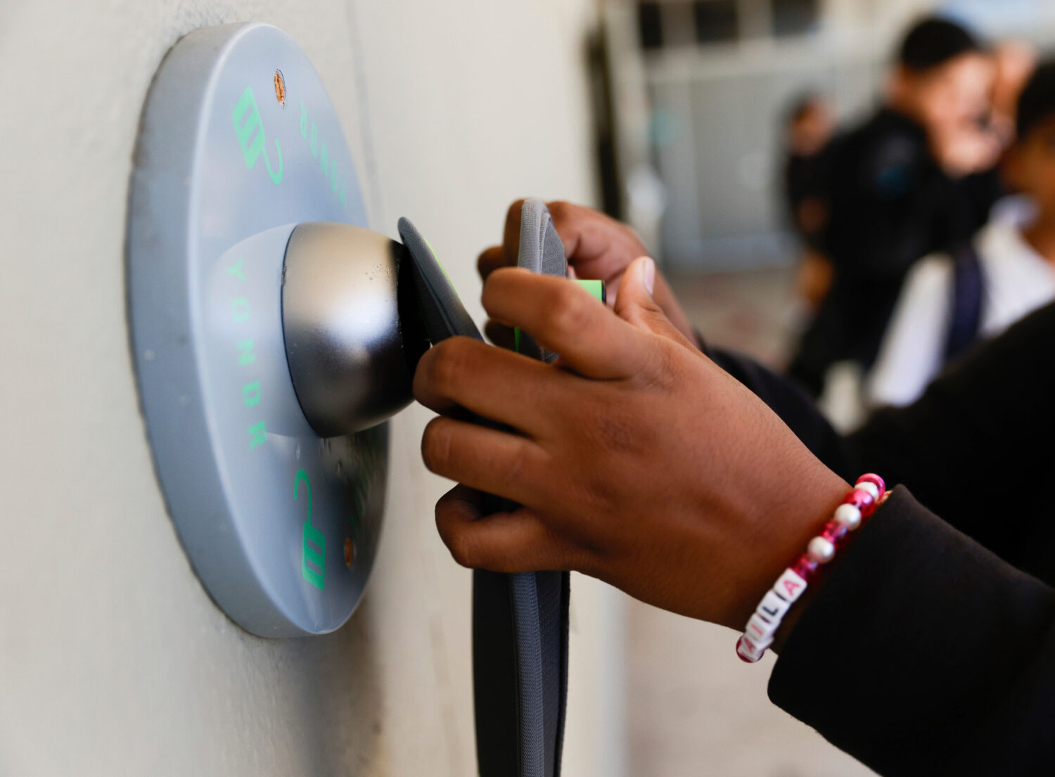FILE - A middle school student unlocks a Yondr pouch on an unlocking base at Bayside Academy while ...