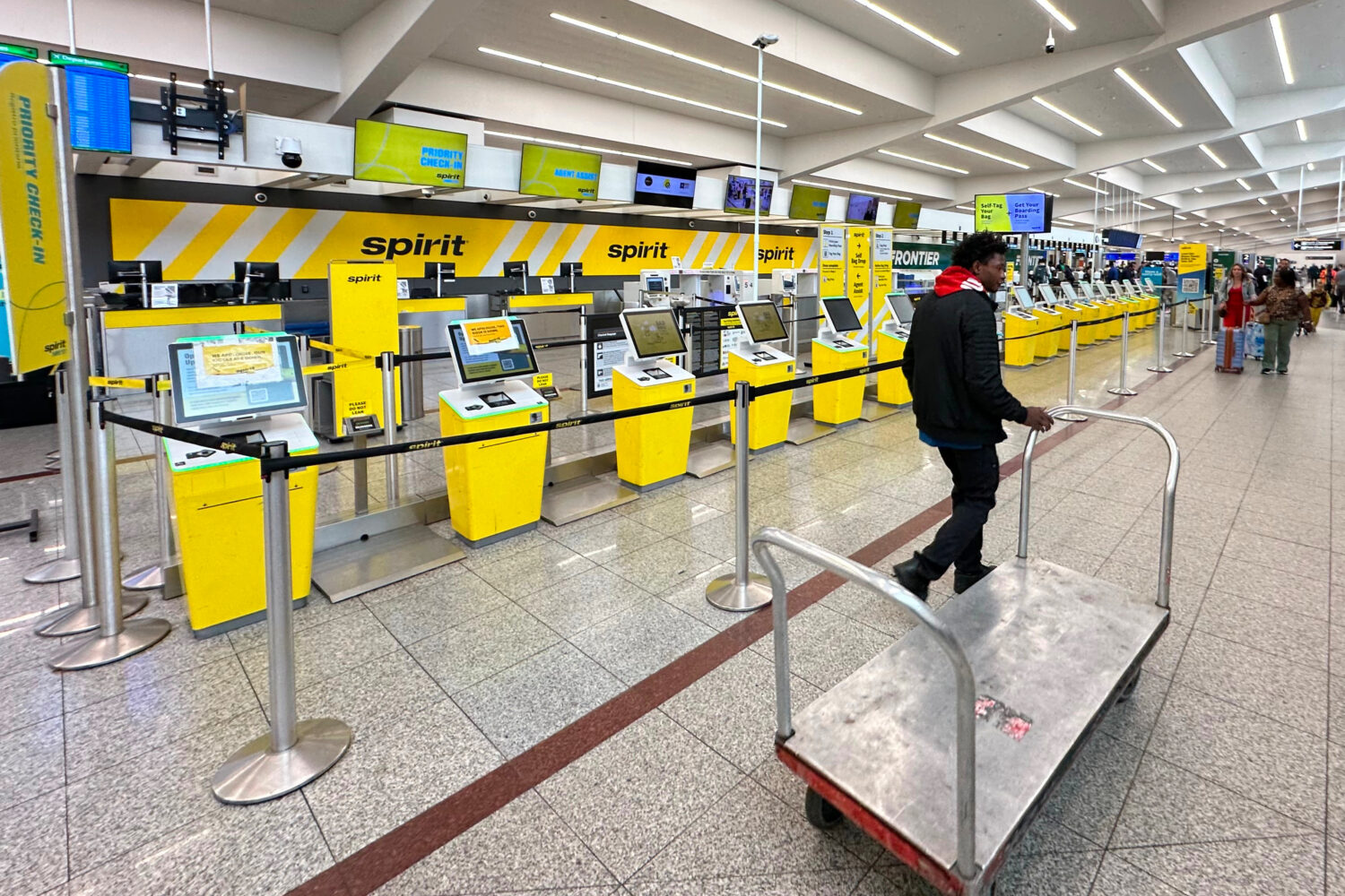Spirit Airlines’ counter is passed by an airport employee after the airline’s shutdown on Satur...