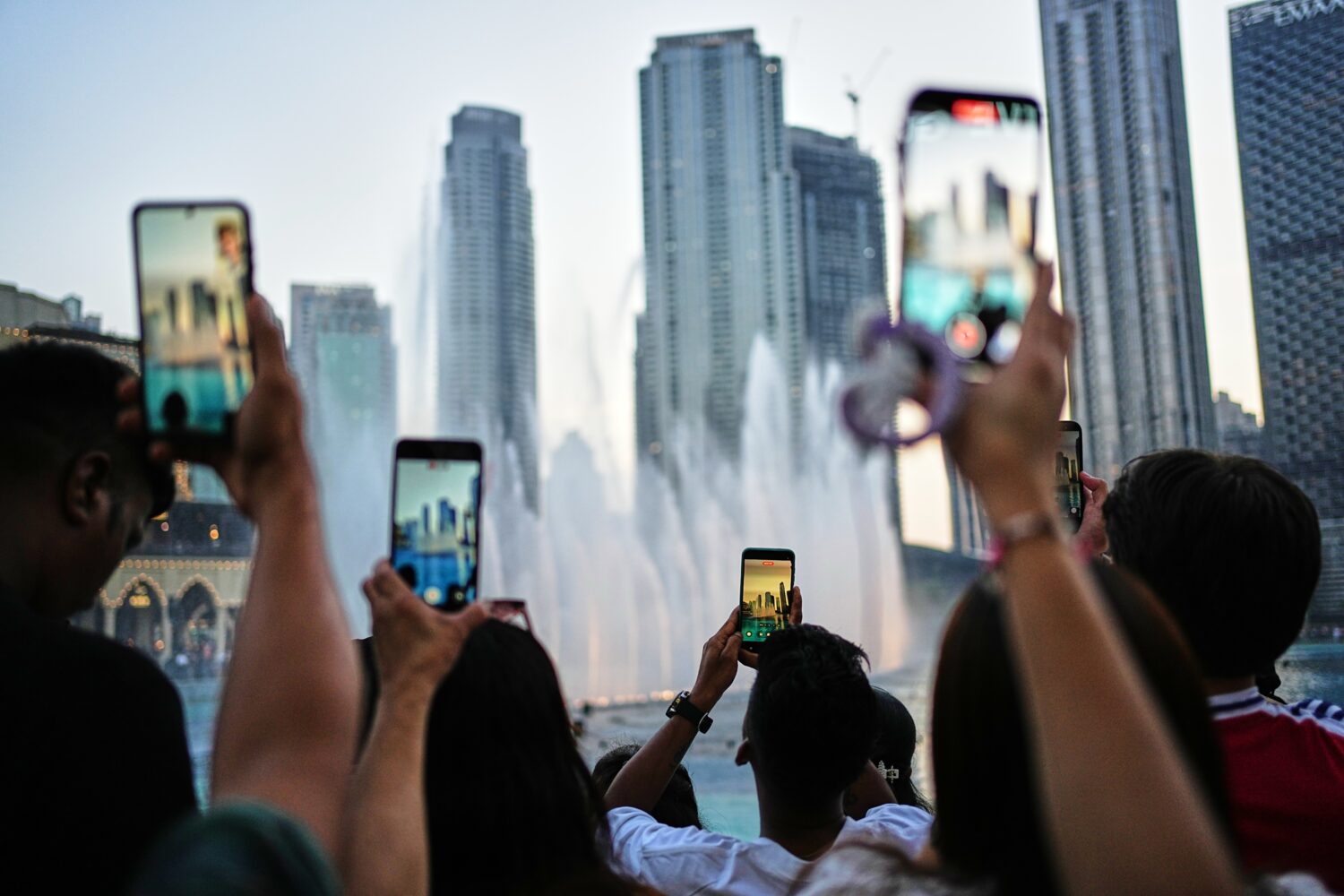 People photograph the Dubai Fountain with skyscrapers in the background outside Dubai Mall on the f...