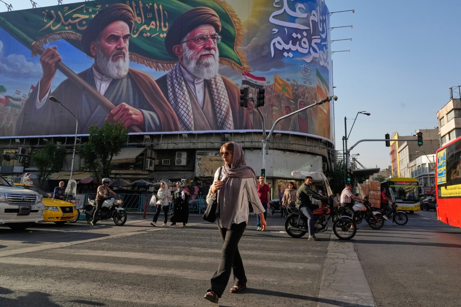 People walk under a banner showing portraits of the late revolutionary founder Ayatollah Khomeini, ...