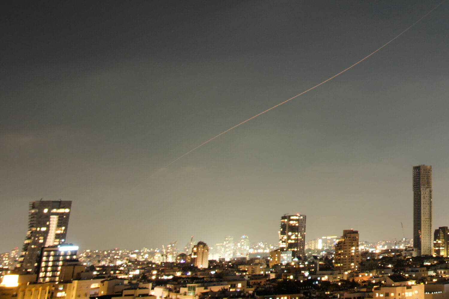 A projectile streaks through the sky over central Israel during an Iranian missile attack, Sunday, ...