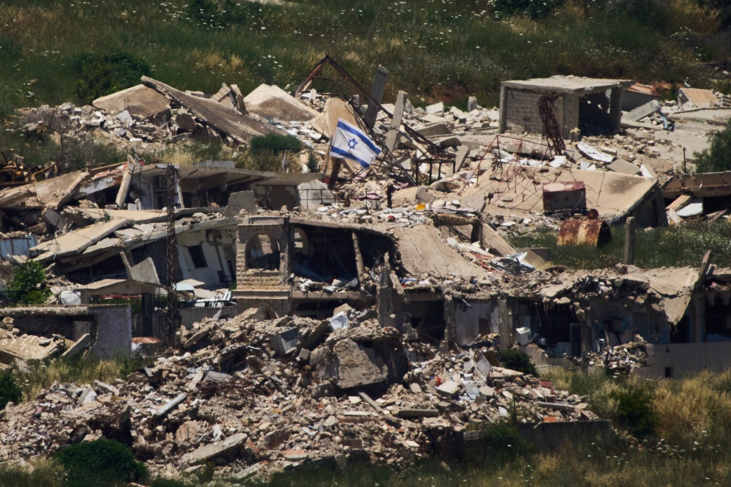 An Israeli flag hangs on a destroyed building in southern Lebanon as seen from northern Israel, Thu...