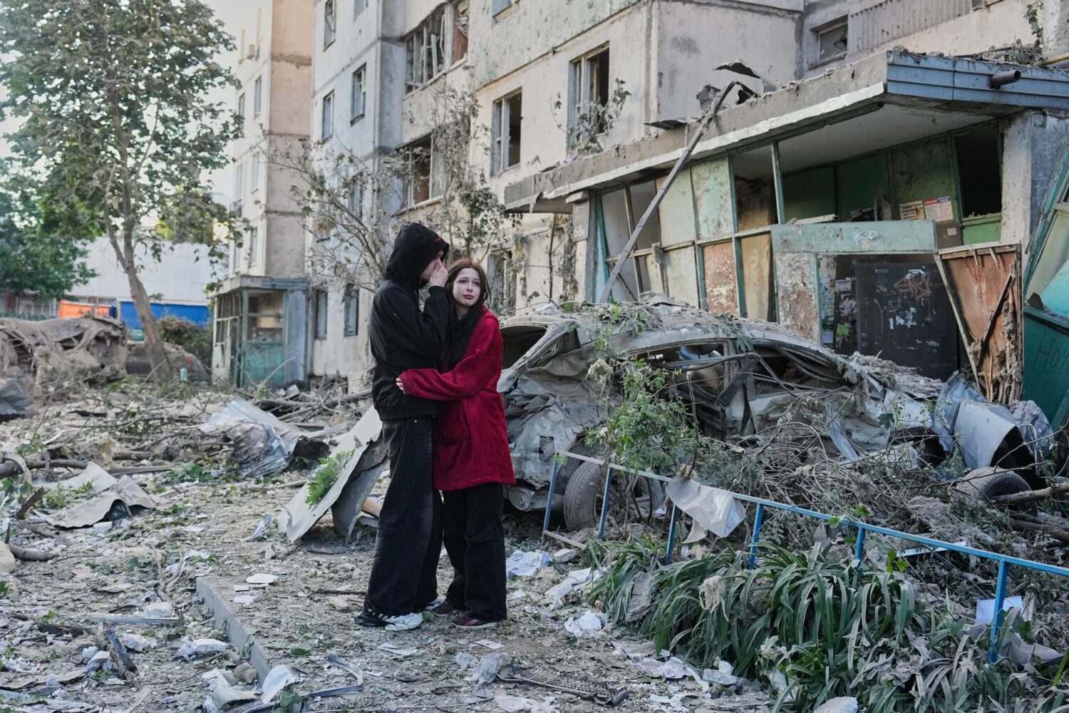 People react as they look at the site of Russian missile strike that hit a residential building in ...