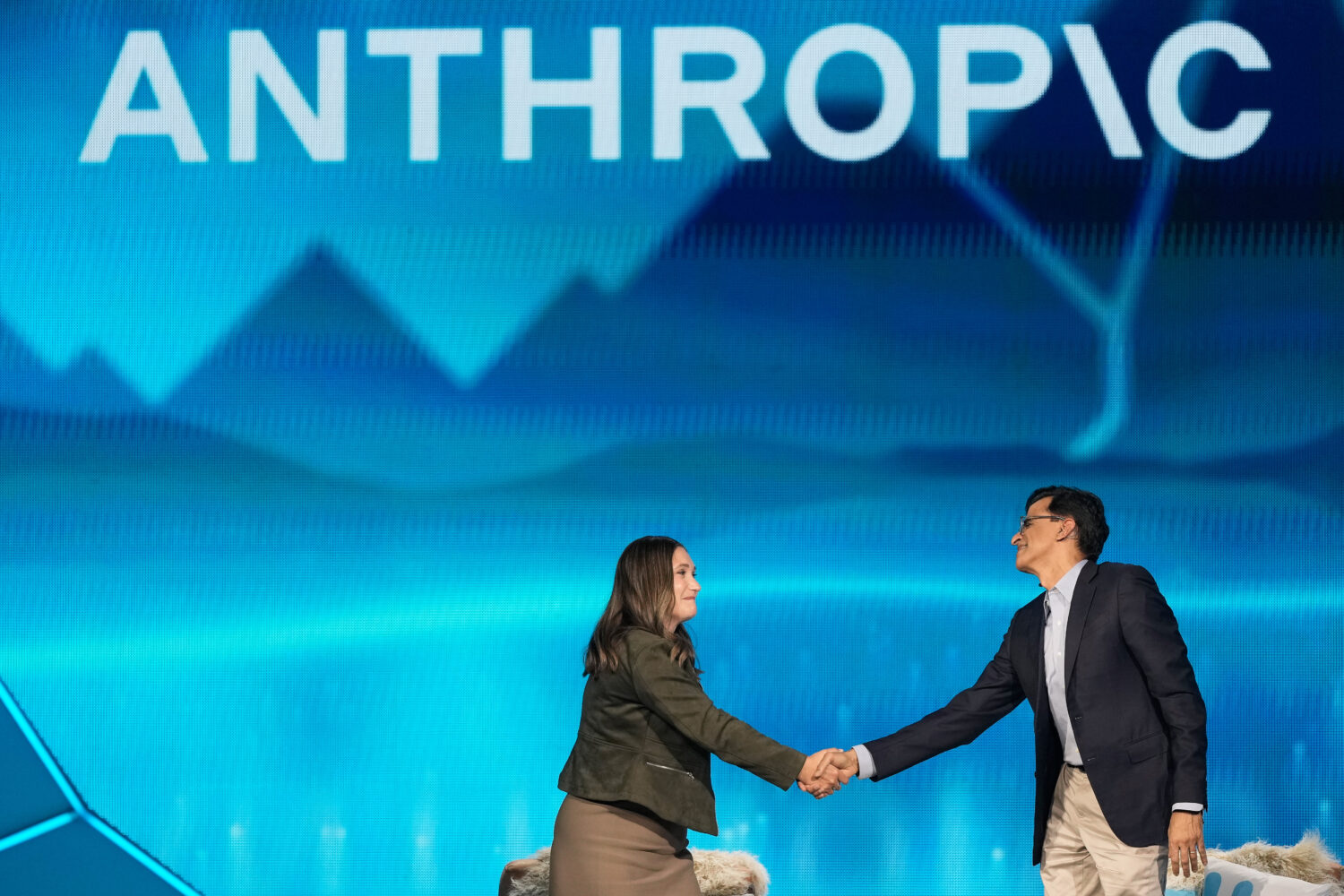 Anthropic co-founder and President Daniela Amodei, left, shakes hands with Snowflake CEO Sridhar Ra...