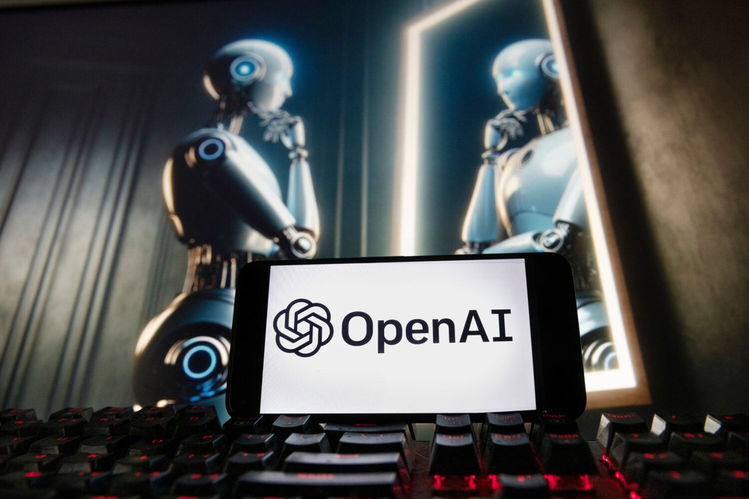 FILE - The OpenAI logo is displayed on a cellphone with an image on a computer monitor generated by...