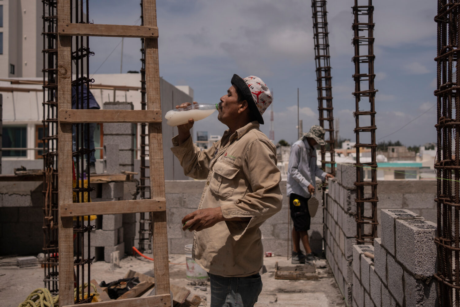 FILE - Jorge Moreno, a worker, drinks flavored water to cope with the heat wave during his workday ...
