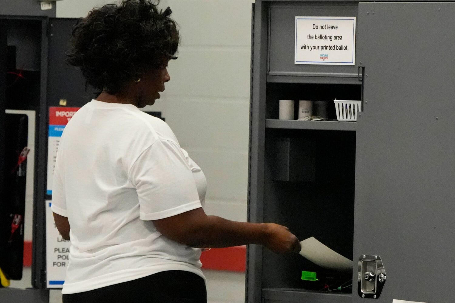 A woman places her paper ballot into a machine after voting in a runoff election at C.T. Martin Rec...