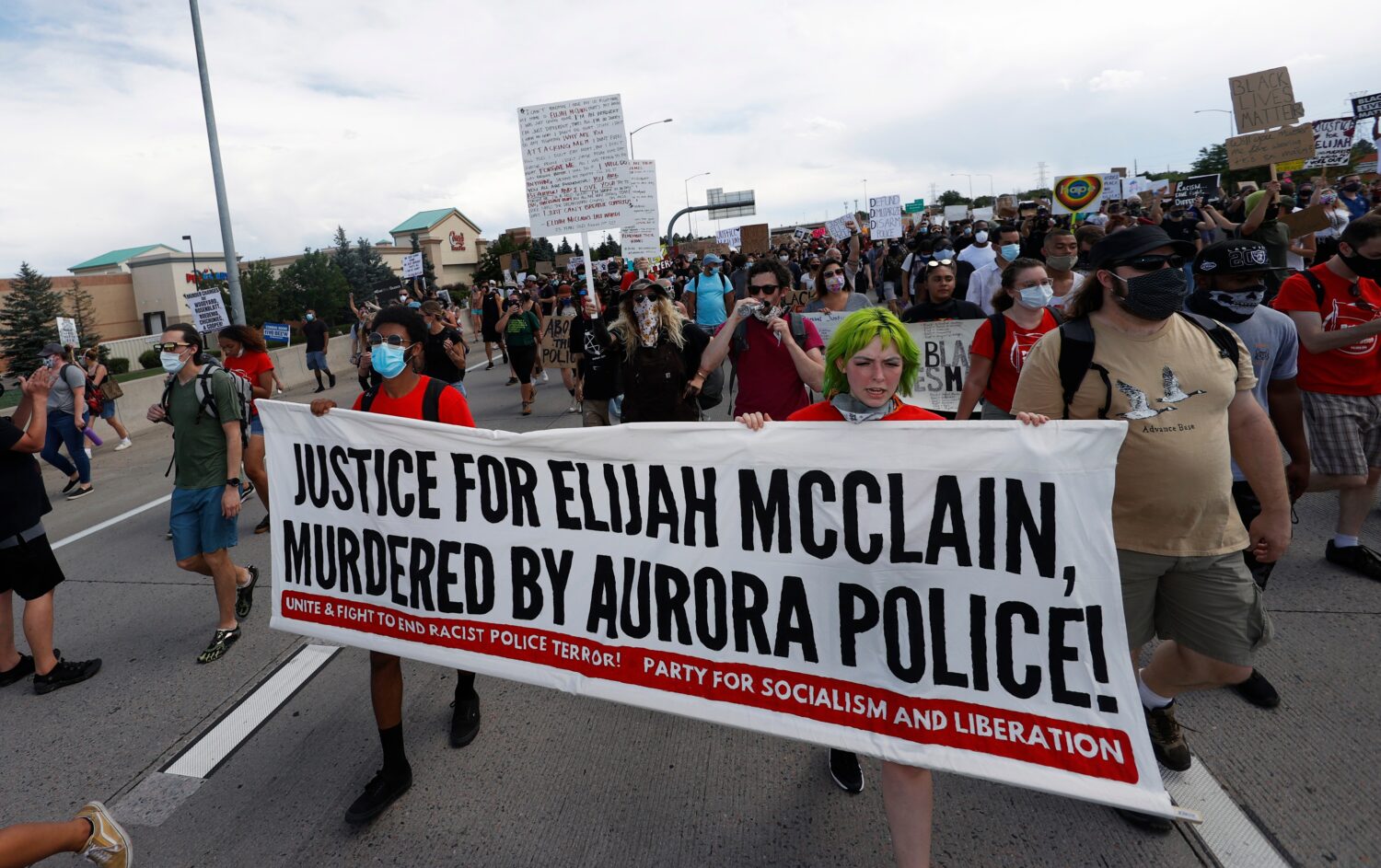 FILE - Demonstrators carry a banner while marching down Interstate 225 during a rally and march ove...