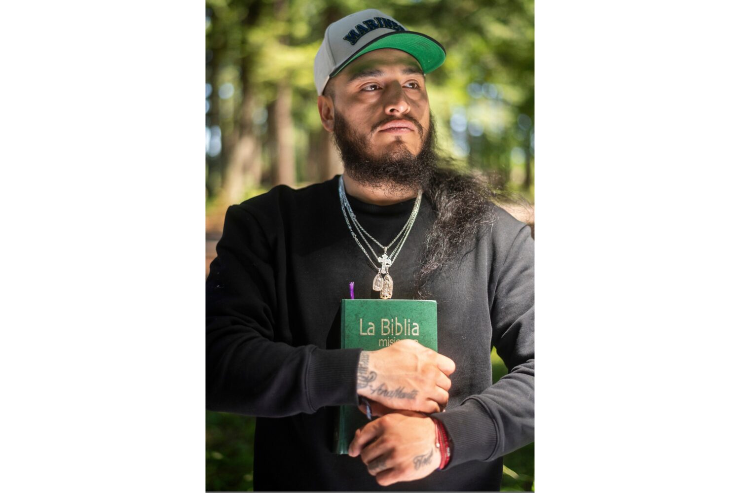 Gabriel Martinez Garcia, 30, holds a Bible close to his chest as tattoos of his parents are visible...