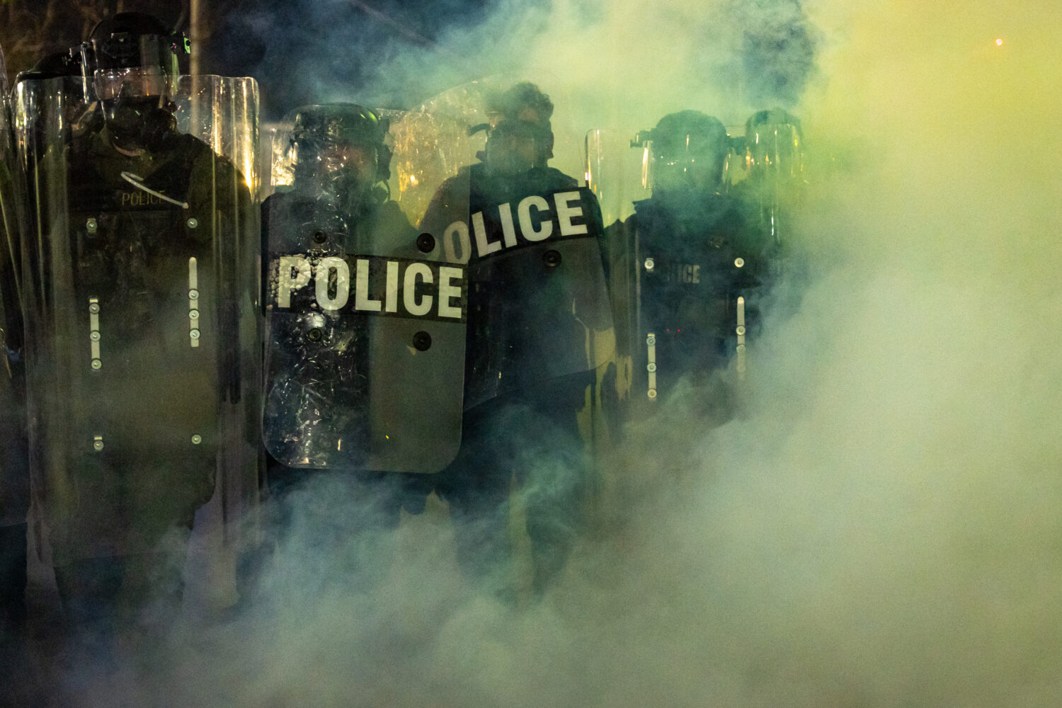 Law Enforcement Officers walk through tear gas chemical irritant during clashes with anti-ICE prote...
