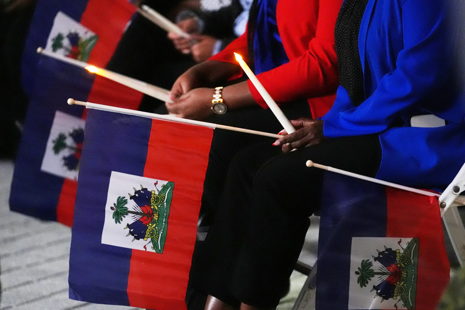 FILE - People hold Haitian flags and candles during a vigil at the Little Haiti Cultural Complex af...