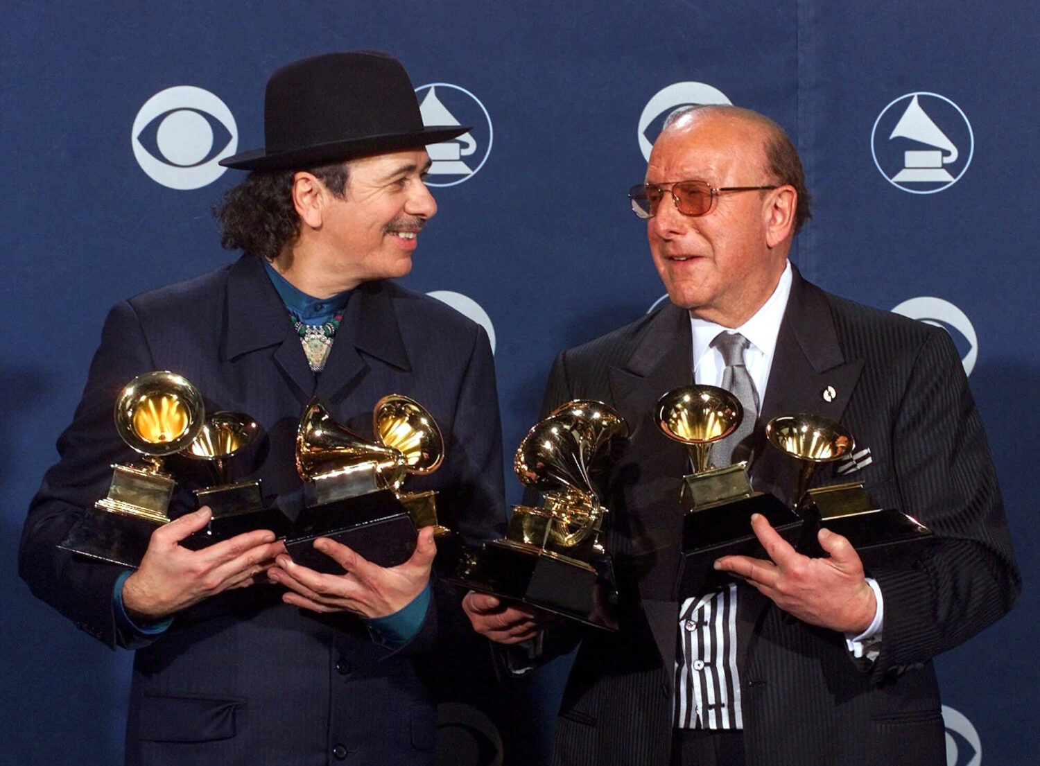 FILE - Carlos Santana, left, and producer Clive Davis pose with their Grammys at the 42nd Grammy Aw...