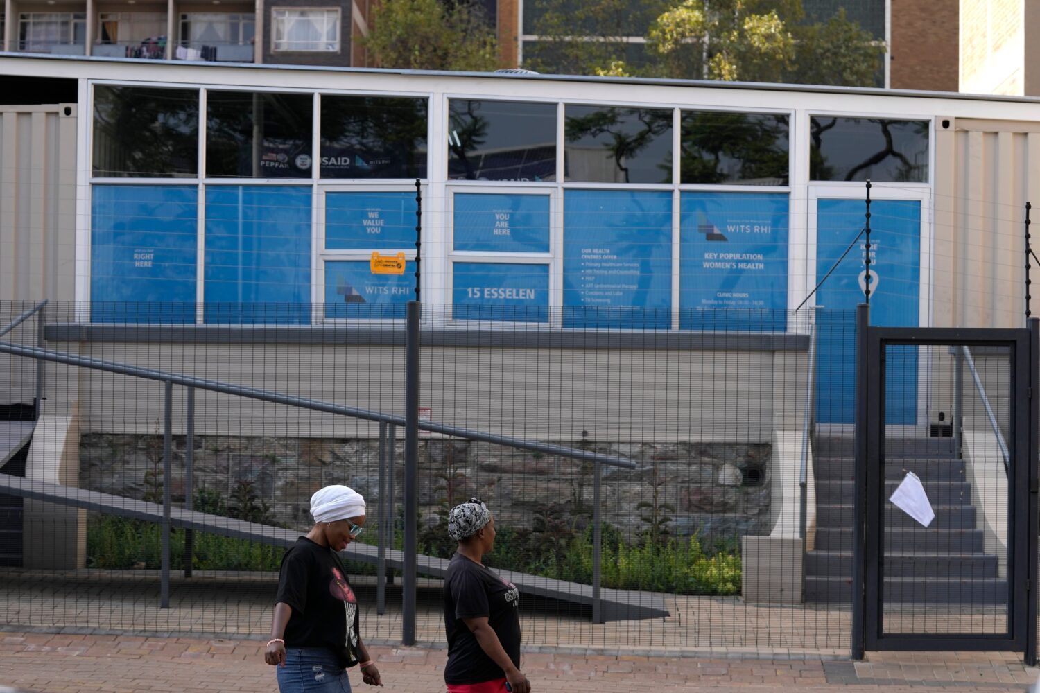 FILE - Women walk past a closed clinic run by WITS Reproductive Health Institute (RHI) as a sign on...