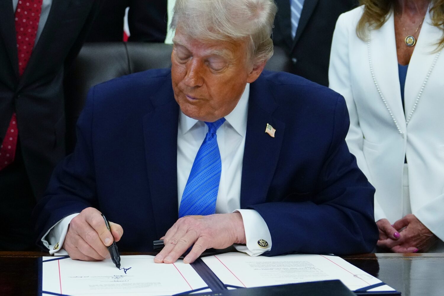 President Donald Trump signs a bill funding immigration enforcement in the Oval Office of the White...