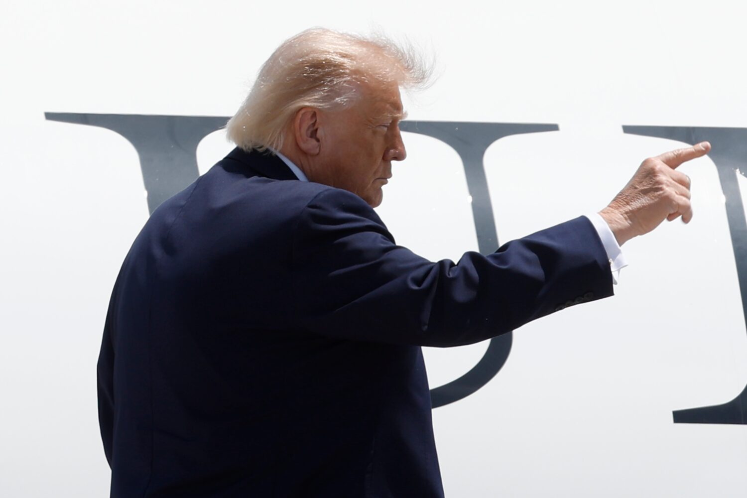 President Donald Trump gestures from the stairs of Air Force One upon his arrival at Joint Base And...