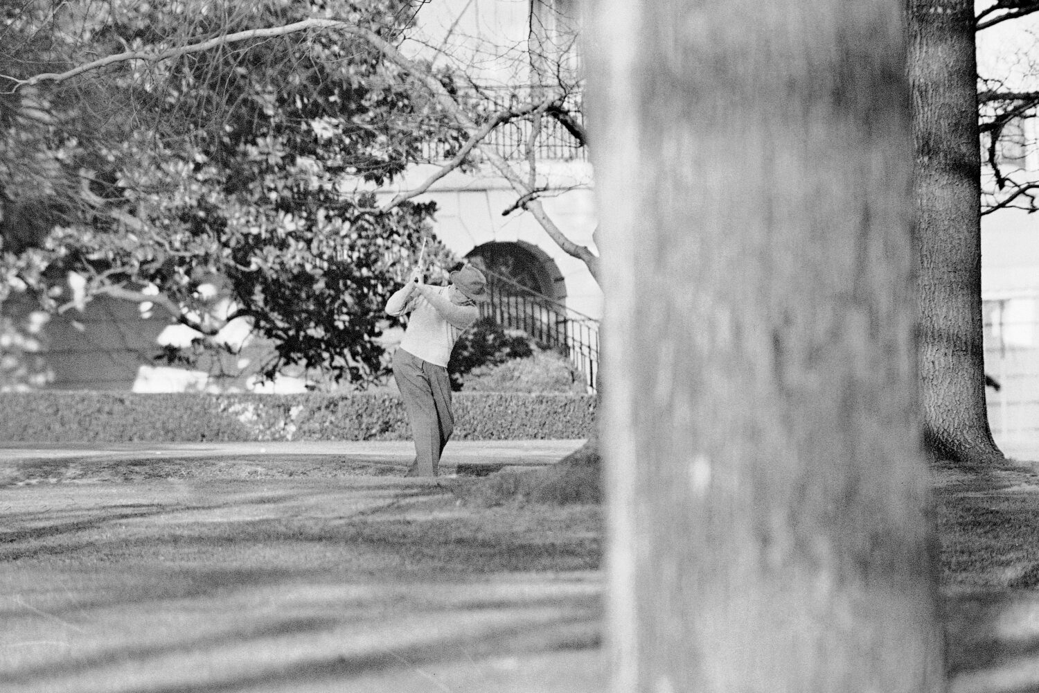 FILE - President Dwight Eisenhower brushes up on his golf game near the putting green on the lawn o...