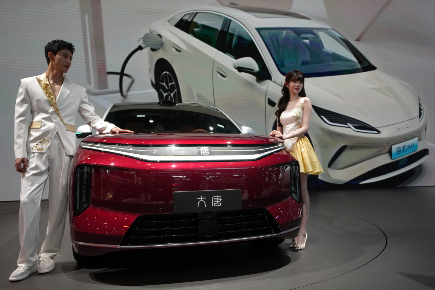 FILE - Models stand next to a latest EV car from Chinese automaker BYD showcased at the Auto China ...