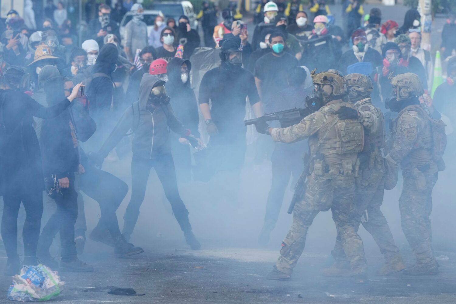 FILE - U.S. Customs and Border Protection agents standoff against demonstrators as tear gas fills t...