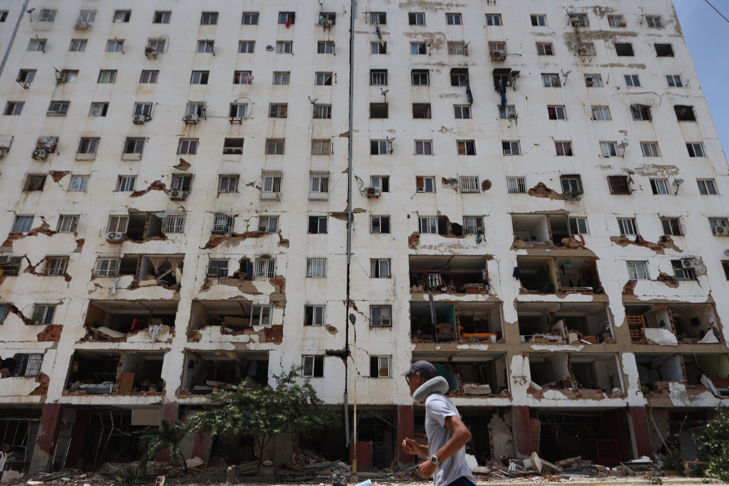 A resident walks past a damaged building a day after an earthquake and several aftershocks struck L...