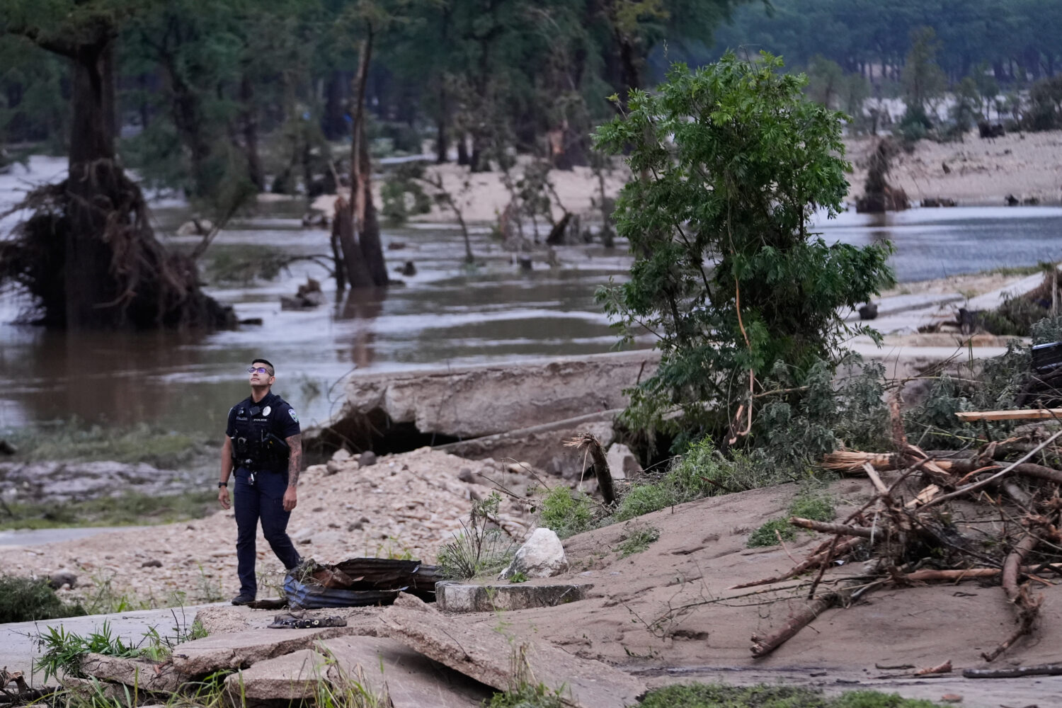 A police officer walks along the Guadalupe River after a series of storms on Friday, July 17, 2026,...