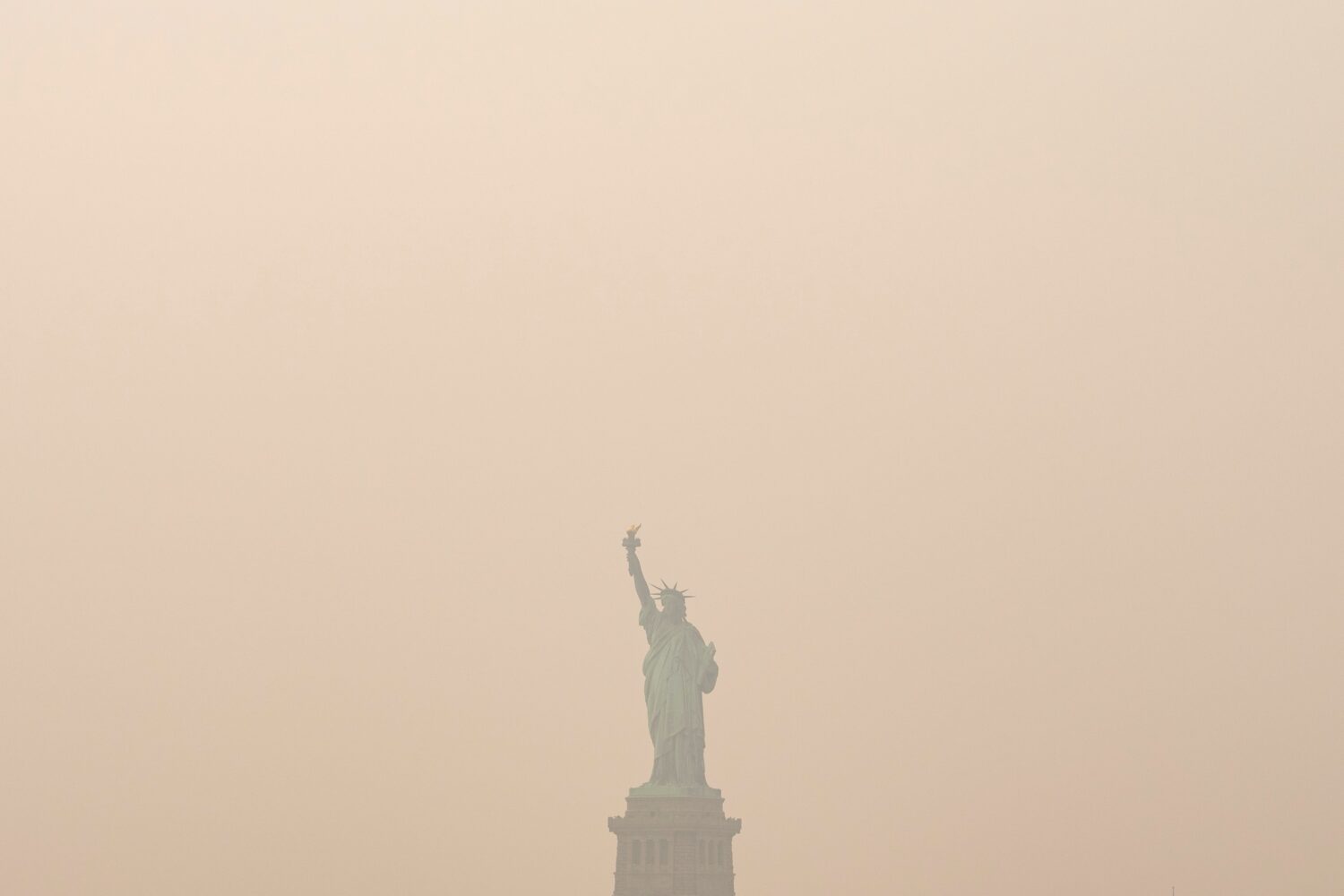 The Statue of Liberty is photographed from the Staten Island Ferry as smoke from wildfires blankets...