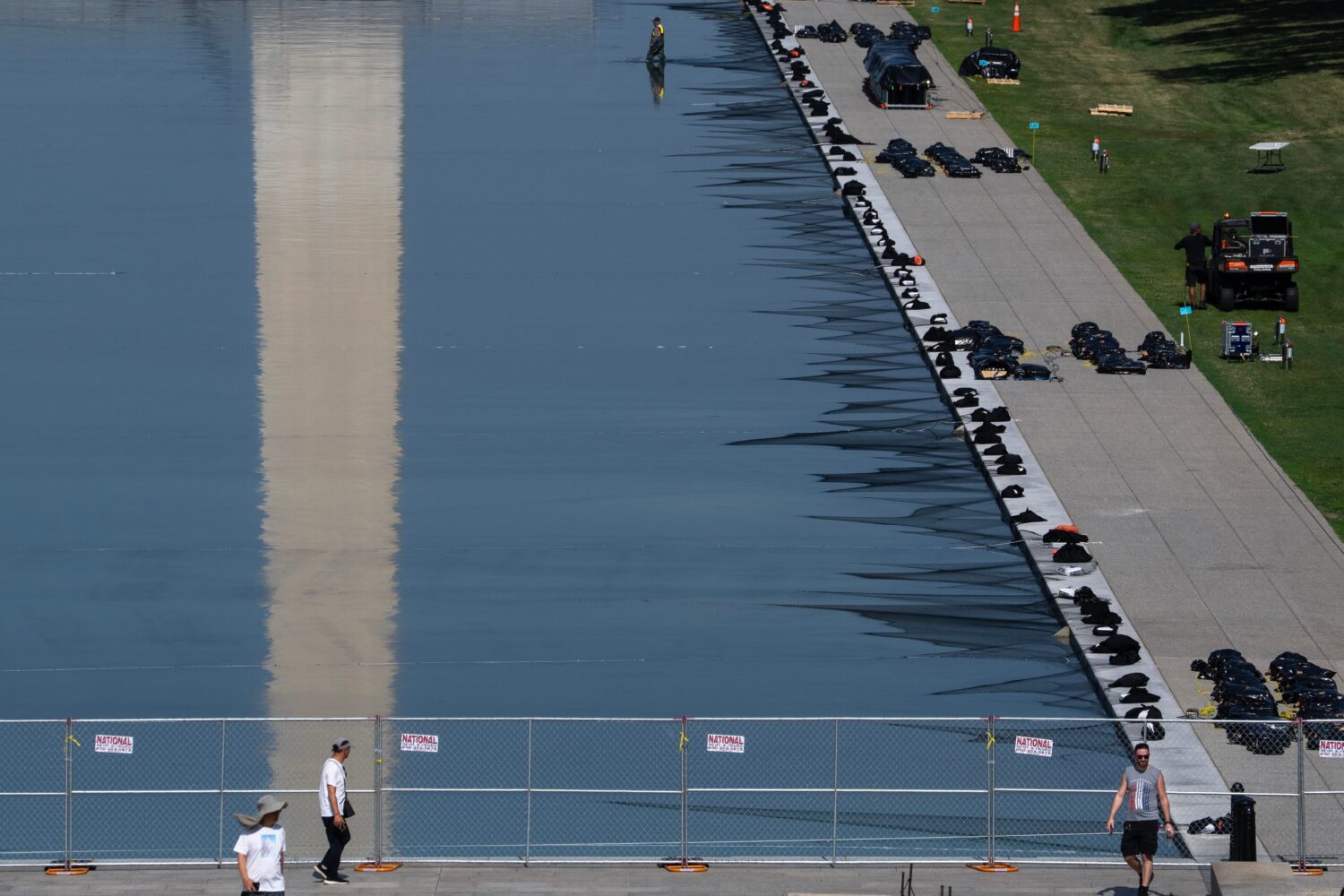Workers install fireworks along the edge of the Lincoln Memorial Reflecting Pool ahead of the Ameri...