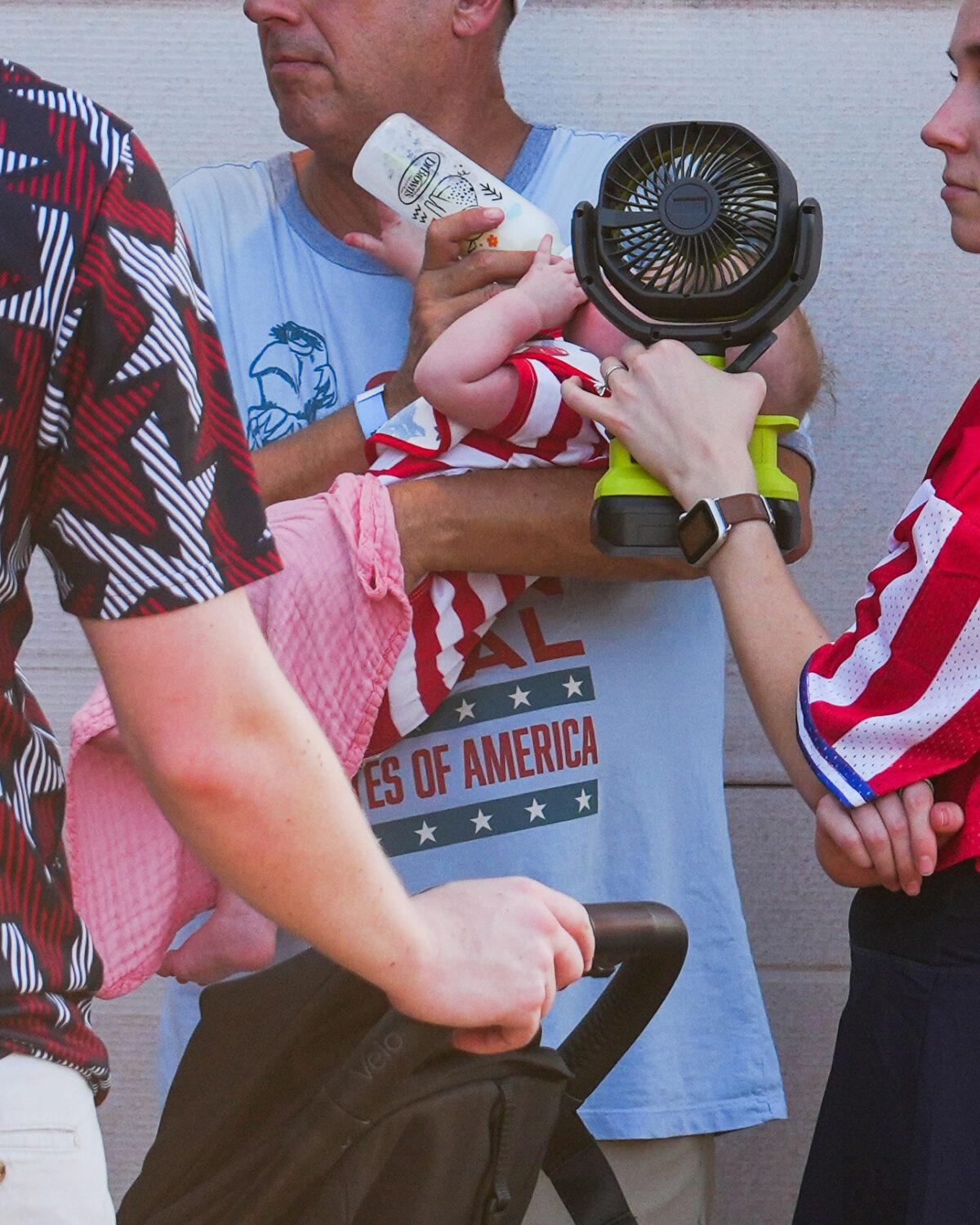 A woman holds a fan in front of a bottle-fed baby at the Great American State Fair, during an extre...