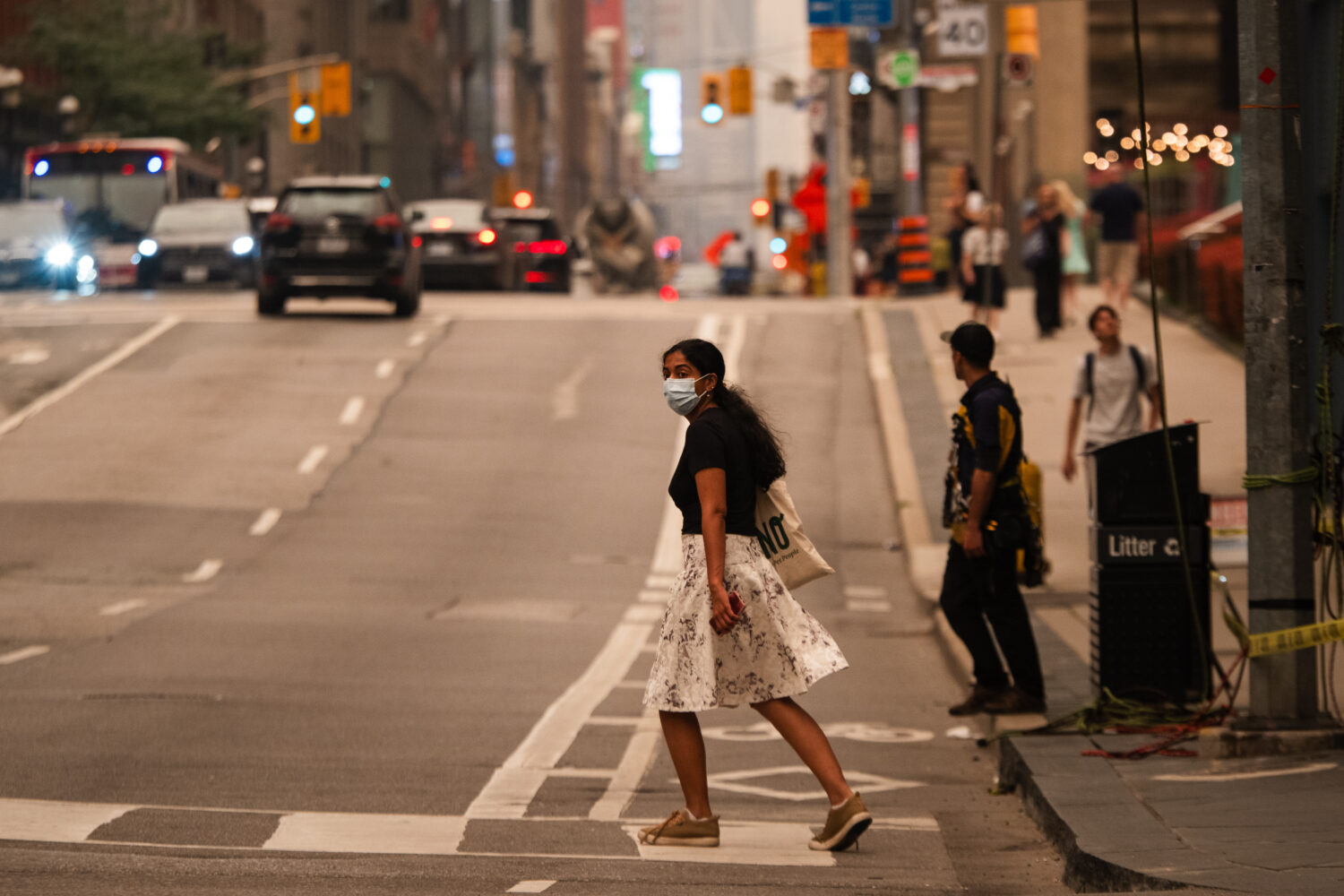 A woman wearing a mask crosses the street in Toronto as wildfire smoke fills the city, on Wednesday...