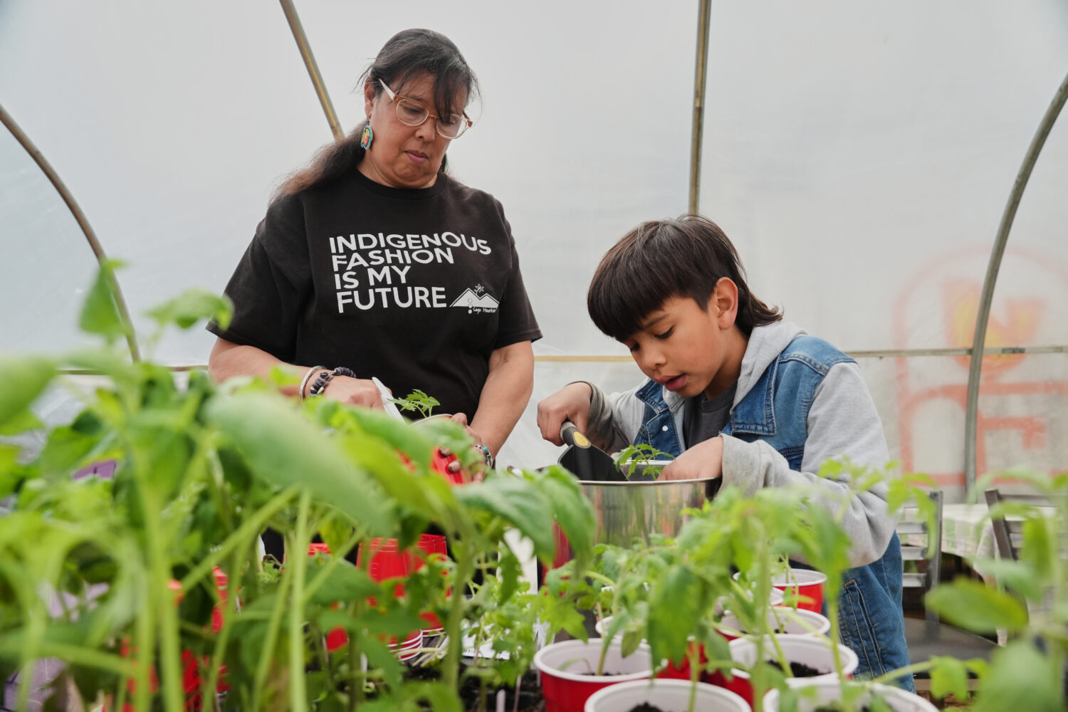 Dawn Spears, left, and her grandson, Giizhig, 9, right, prepare tomatoes for planting Tuesday, Apri...