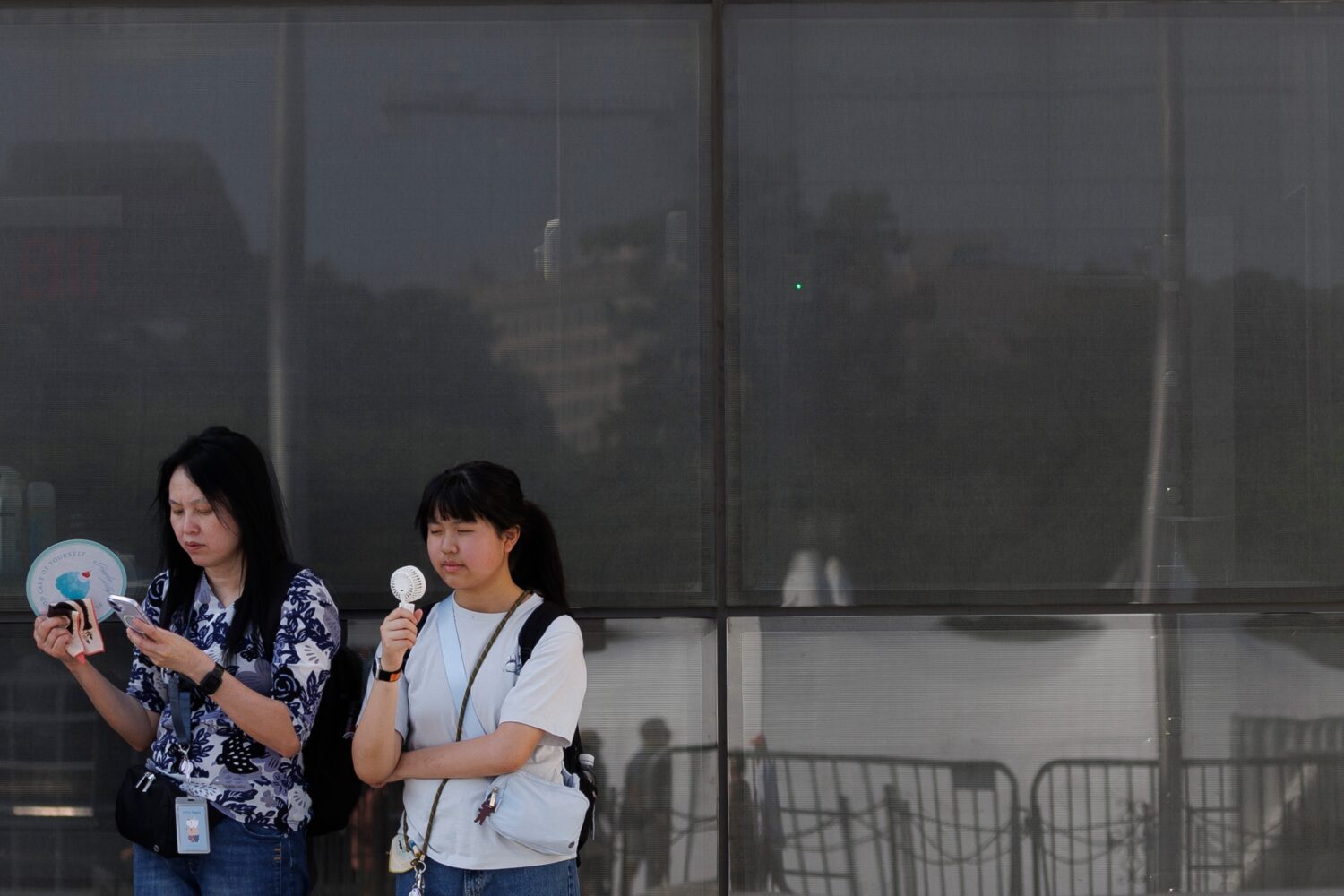 FILE - Visitors use fans as as they wait to enter the Washington Monument, July 1, 2026, in Washing...
