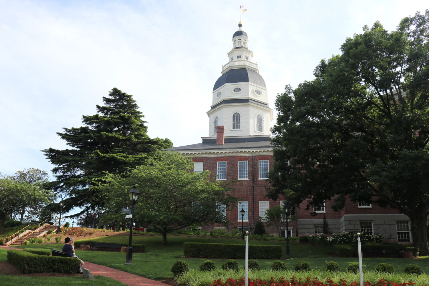 A couple sits on a bench on the grounds of the Maryland State House in Annapolis, Md., Saturday, Ju...