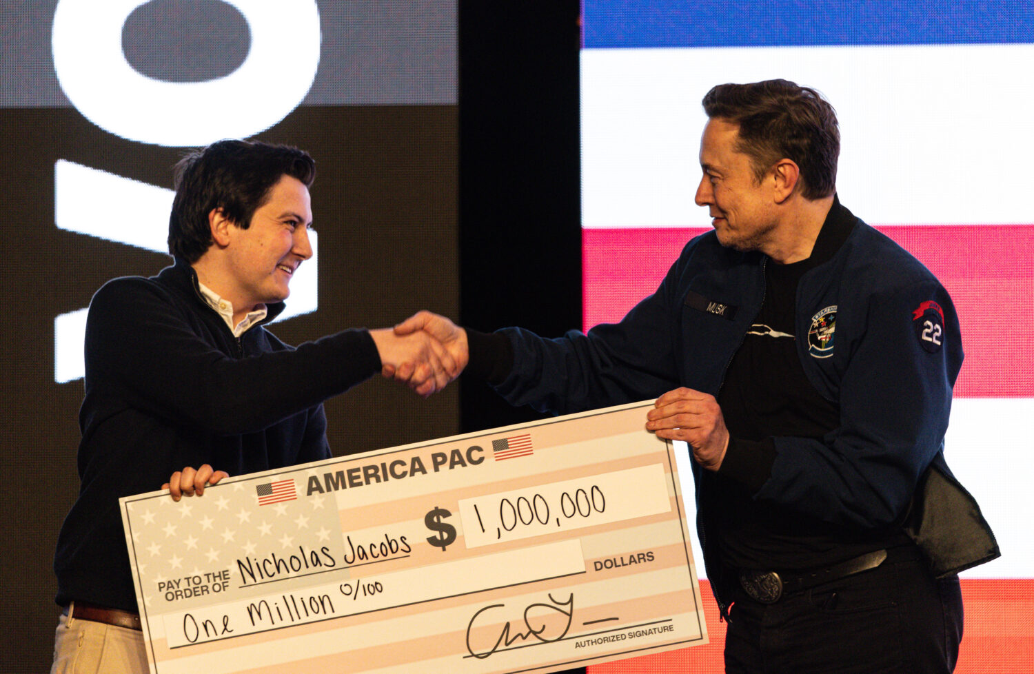 FILE - Elon Musk hands over a million dollar check to Nicholas Jacobs during a town hall in Green B...