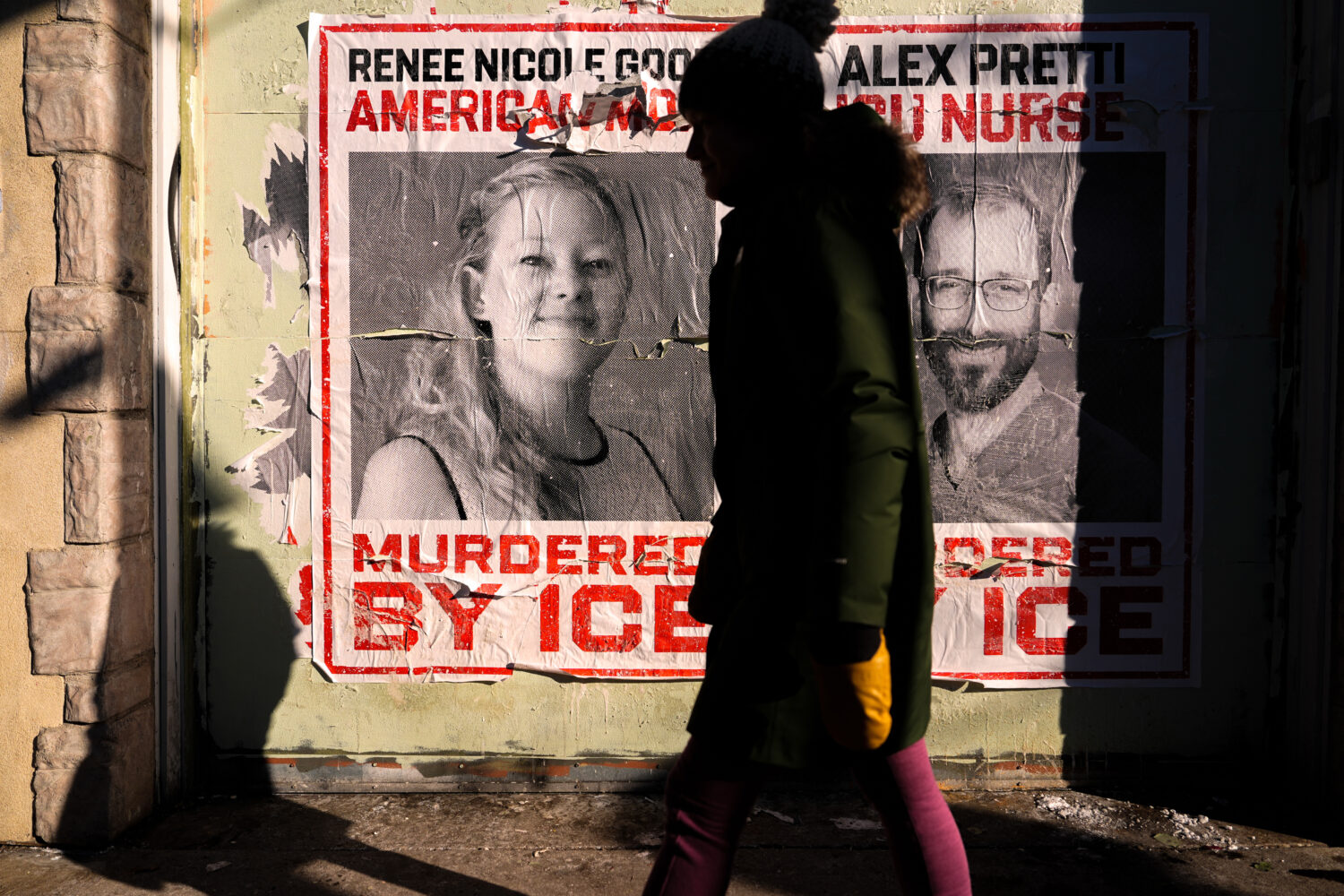 FILE - A woman walks by posters of Renee Good and Alex Pretti during a solidarity bike ride for Pre...