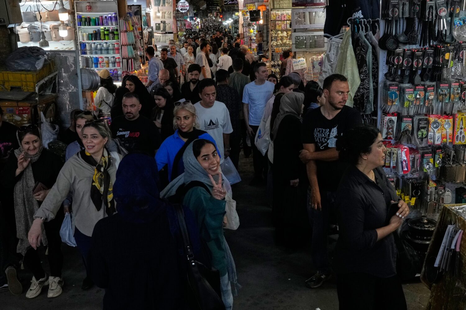 A woman flashes a victory sign while walking at Tehran's traditional main bazaar, Iran, Thursday, J...