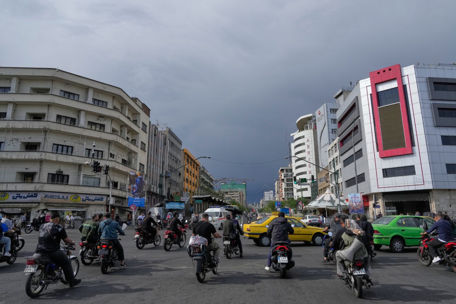 FILE - Motorbikes and cars pass through an intersection in downtown Tehran, Iran, May 17, 2026. (AP...