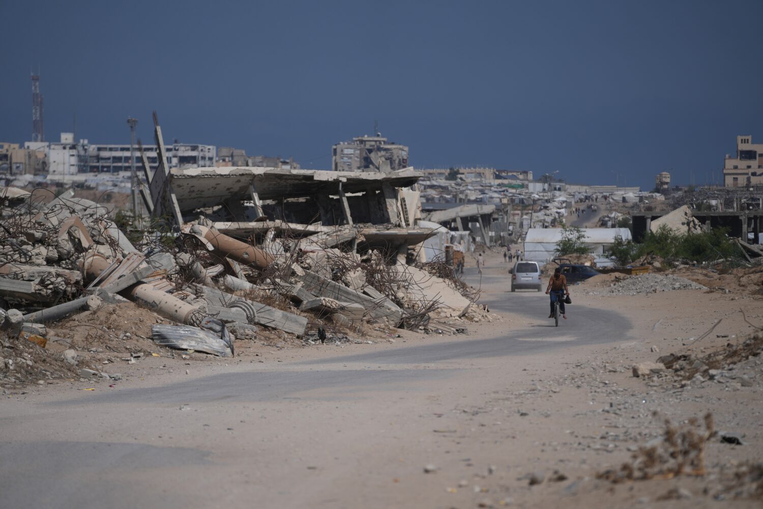 A Palestinian man rides his bicycle by the rubble of buildings that were destroyed during the Israe...