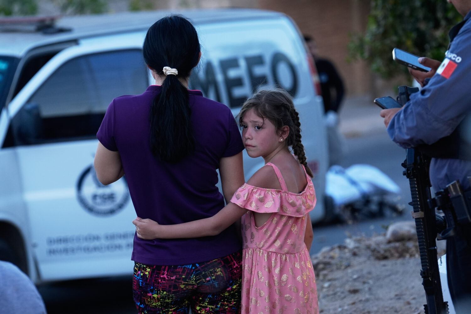 FILE - Relatives of a victim of a fatal armed attack look on as forensic workers investigate the sc...