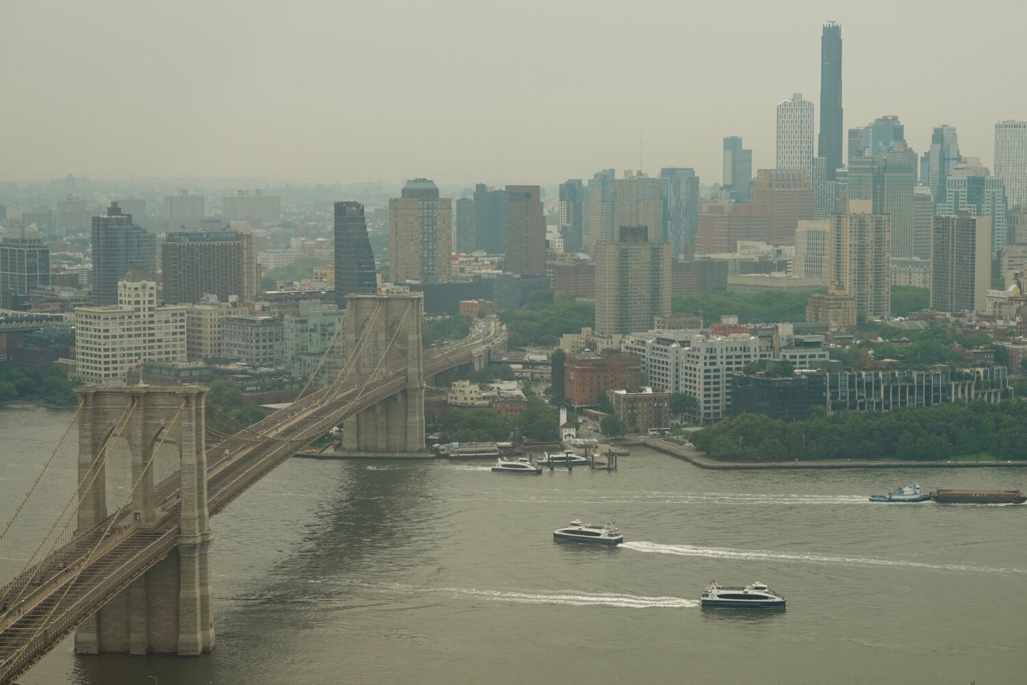 Boats maneuver the East River near the Brooklyn Bridge as smoke from wildfires blankets the sky Thu...