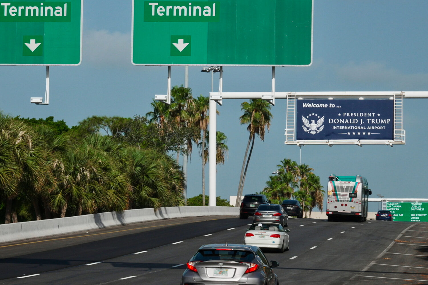 Airport visitors drive under a sign displaying the name of the rebranded Donald J. Trump Internatio...