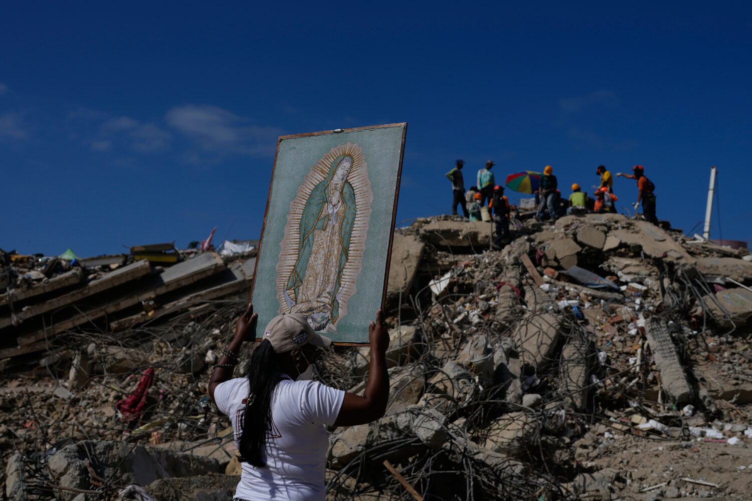 A woman holds a painting of the Virgin Mary as she accompanies a Catholic priest supporting people ...