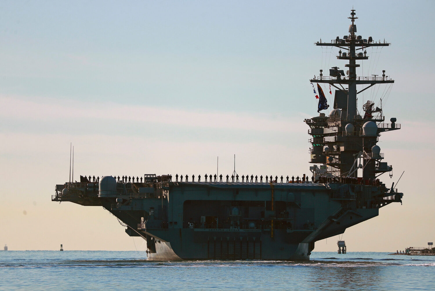 FILE - Sailors and marines line the deck of aircraft carrier USS Abraham Lincoln (CVN-72) as it dep...