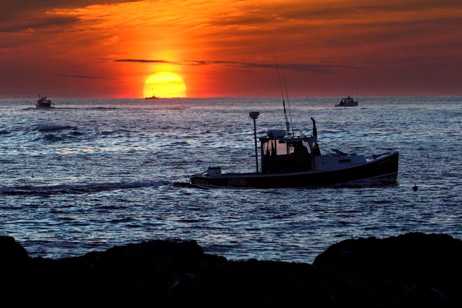 FILE - Lobster fishermen work at sunrise, Sept. 8, 2022, off Kennebunkport, Maine. (AP Photo/Robert...