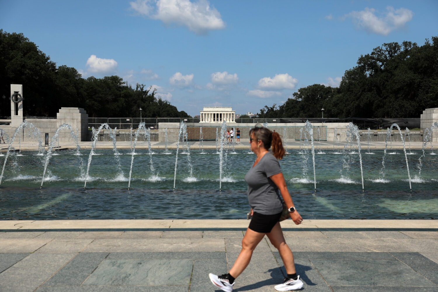 A woman walks near the fountain at the WWII Memorial, in Washington, Wednesday, July 29, 2026. (AP ...